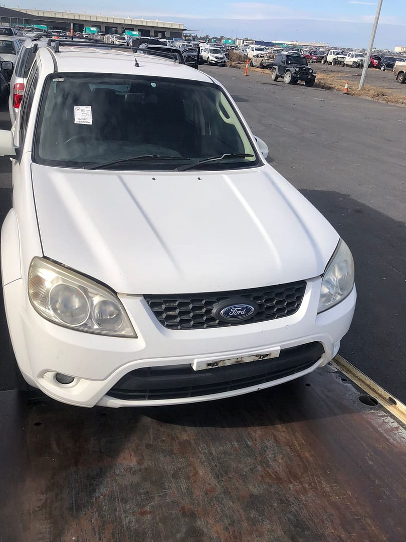Light-coloured hatchback in a vehicle yard